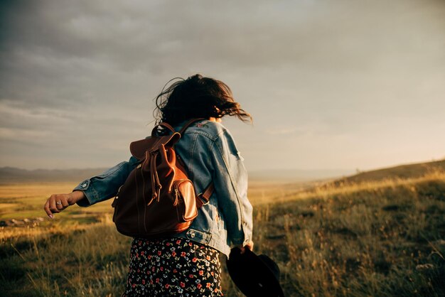 Hintergrundansicht einer Frau, die auf dem Feld gegen den Himmel steht