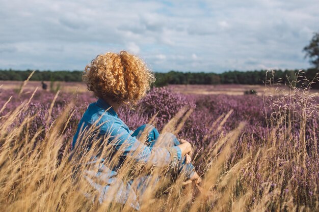 Hintergrundansicht einer Frau, die auf dem Feld gegen den Himmel steht