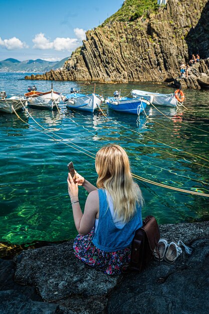 Hintergrundansicht einer Frau, die auf einem Felsen im Wasser sitzt