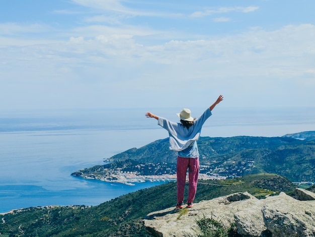 Hintergrundansicht einer Frau, die auf einer Klippe gegen die Landschaft steht