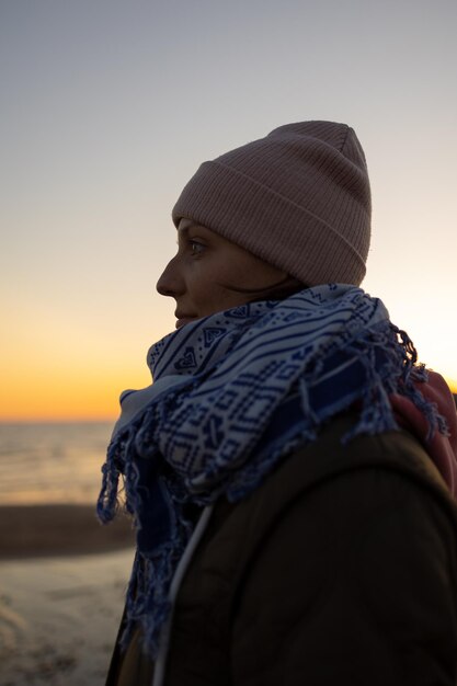 Hintergrundansicht einer Frau, die bei Sonnenuntergang am Strand gegen den Himmel steht