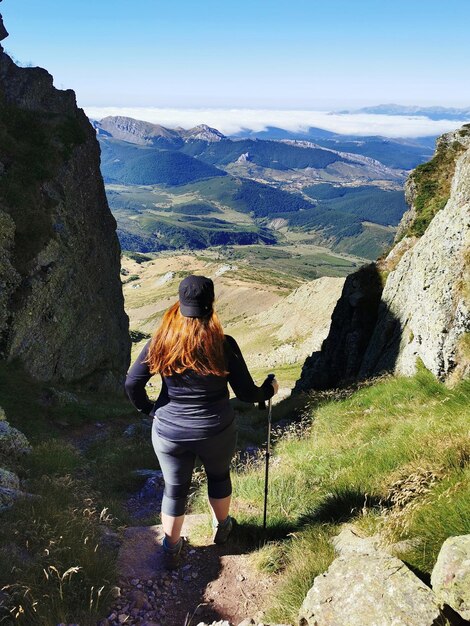 Foto hintergrundansicht einer frau, die die berge gegen den himmel betrachtet