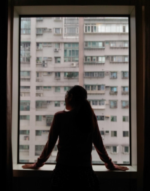 Hintergrundansicht einer Frau, die durch das Fenster schaut