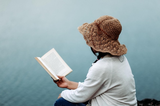 Hintergrundansicht einer Frau, die ein Buch gegen das Wasser hält