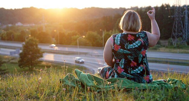 Foto hintergrundansicht einer frau, die ein ok-zeichen auf dem feld gegen einen klaren himmel zeigt