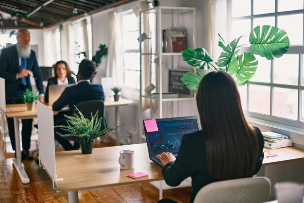 Hintergrundansicht einer Frau, die einen Laptop im Büro benutzt