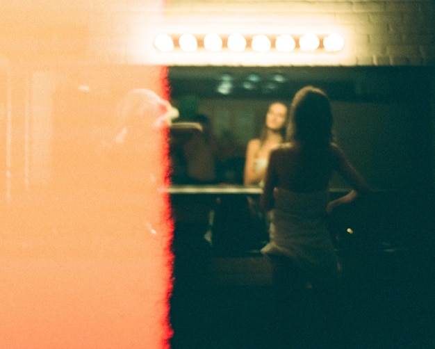 Foto hintergrundansicht einer frau, die in einem beleuchteten raum vor dem spiegel steht