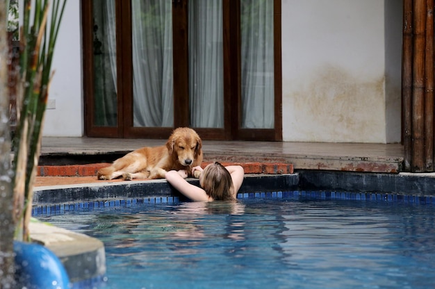 Hintergrundansicht einer Frau, die in einem Schwimmbad von einem Hund schwimmt