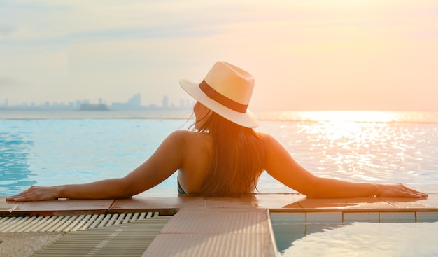 Hintergrundansicht einer Frau, die sich im Schwimmbad gegen den Himmel erfreut