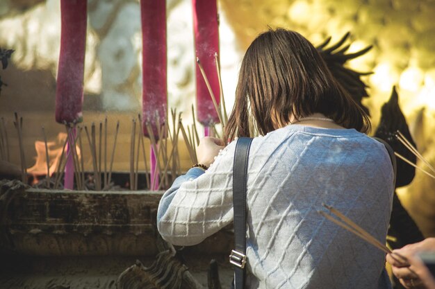 Foto hintergrundansicht einer frau, die während des gebets im tempel weihrauch hält