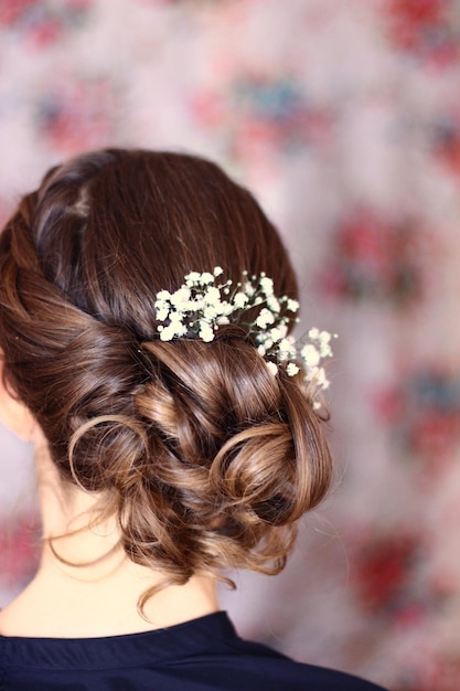 Hintergrundansicht einer Frau mit braunen Haaren, die Blumen trägt