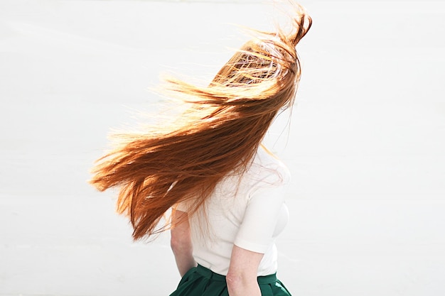 Hintergrundansicht einer Frau mit braunen Haaren, die vor einem weißen Hintergrund steht