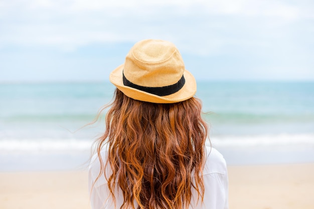 Hintergrundansicht einer Frau mit Hut am Strand