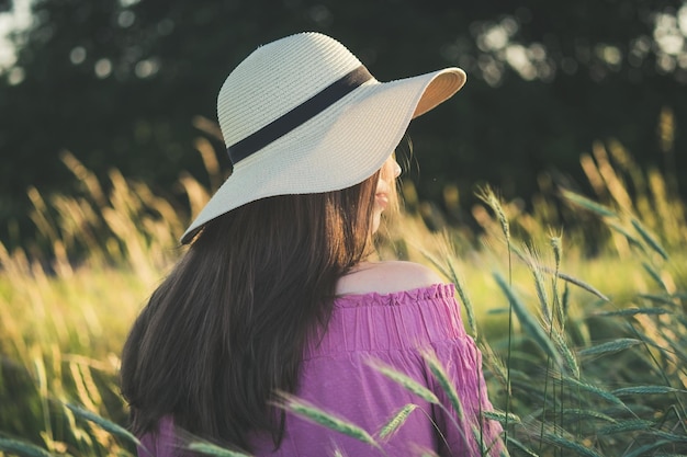 Hintergrundansicht einer Frau mit Hut auf einem grasbewachsenen Feld