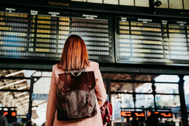Hintergrundansicht einer Frau mit Rucksack, die am Bahnhof steht