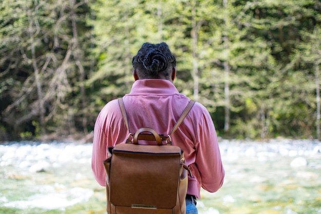 Hintergrundansicht einer Frau mit Rucksack, die im Wald steht