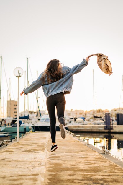 Foto hintergrundansicht einer jungen frau, die bei sonnenuntergang im hafen springt