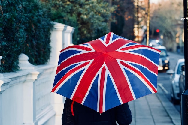 Foto hintergrundansicht einer laufenden person, die einen britischen flaggenschirm hält