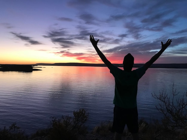 Foto hintergrundansicht einer silhouette, die bei sonnenuntergang am see gegen den himmel steht