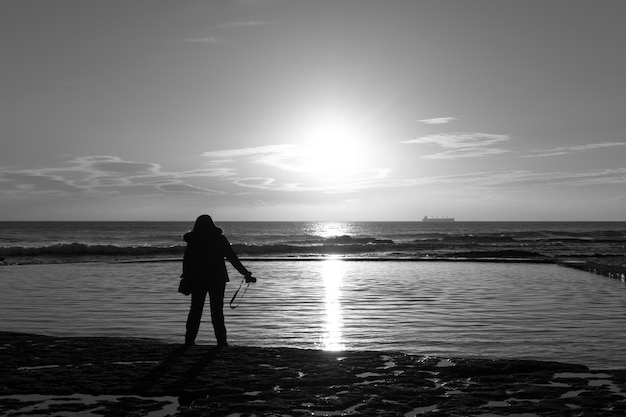 Foto hintergrundansicht einer silhouette von einer frau, die bei sonnenuntergang am strand steht