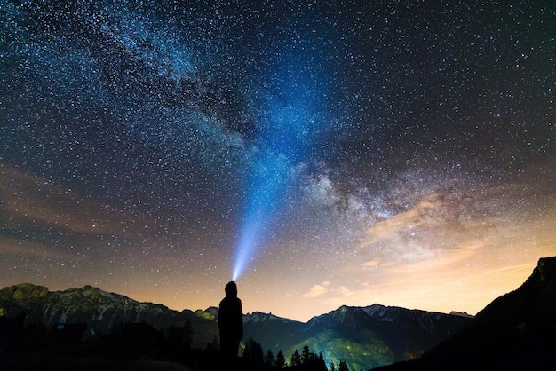 Hintergrundansicht einer Silhouette von einer Person, die an Bergen gegen das Sternenfeld steht