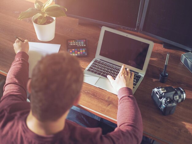 Hintergrundansicht eines Geschäftsmanns mit Laptop am Schreibtisch im Büro