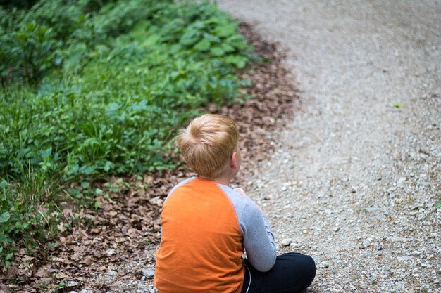 Foto hintergrundansicht eines jungen, der auf einem fußweg sitzt