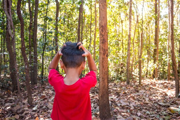 Foto hintergrundansicht eines jungen mit den händen in den haaren, der im wald steht