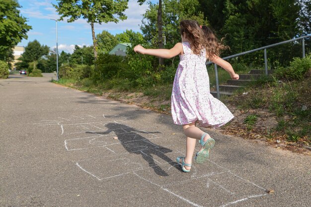 Foto hintergrundansicht eines mädchens, das auf der straße hopscotch spielt