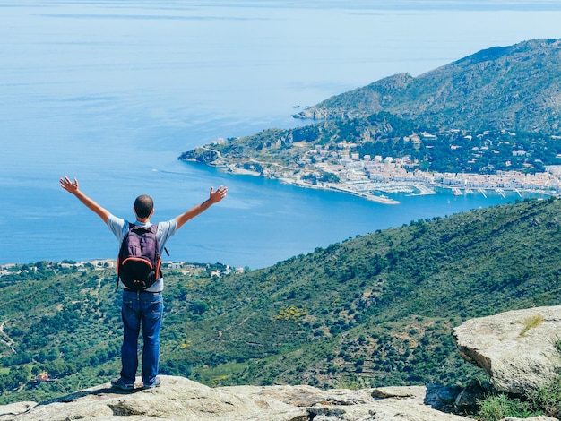 Hintergrundansicht eines Mannes, der am Meer auf einem Felsen steht