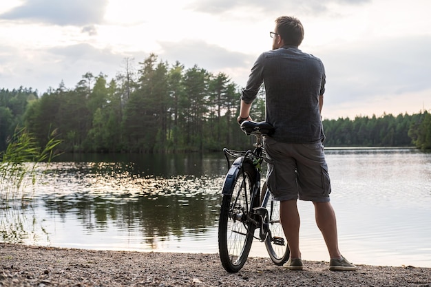 Foto hintergrundansicht eines mannes, der am see gegen den himmel fahrrad fährt