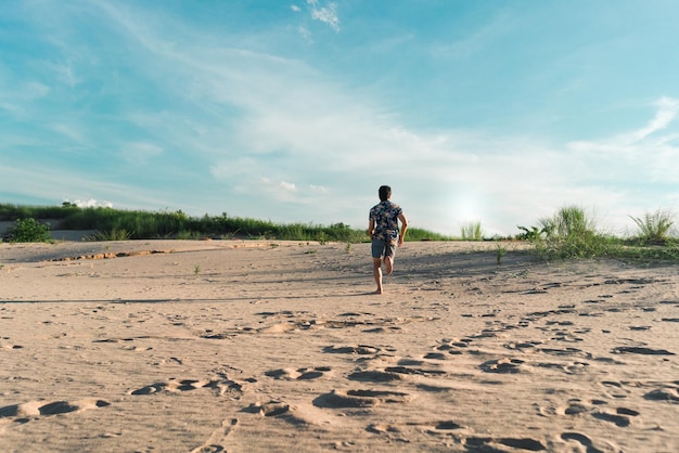 Hintergrundansicht eines Mannes, der am Strand auf Sand rennt