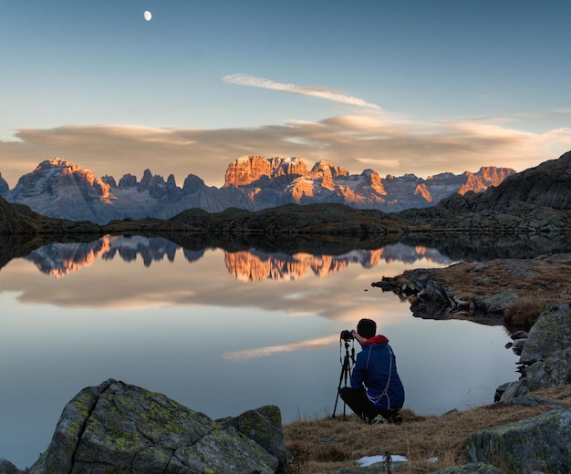 Foto hintergrundansicht eines mannes, der am ufer des sees vor bergen fotografiert