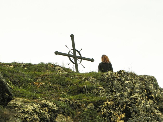 Hintergrundansicht eines Mannes, der auf einem Felsen gegen den Himmel sitzt