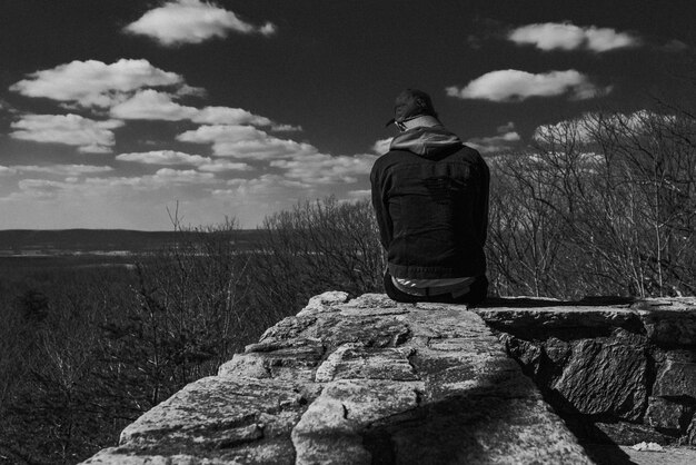 Foto hintergrundansicht eines mannes, der auf einem felsen sitzt