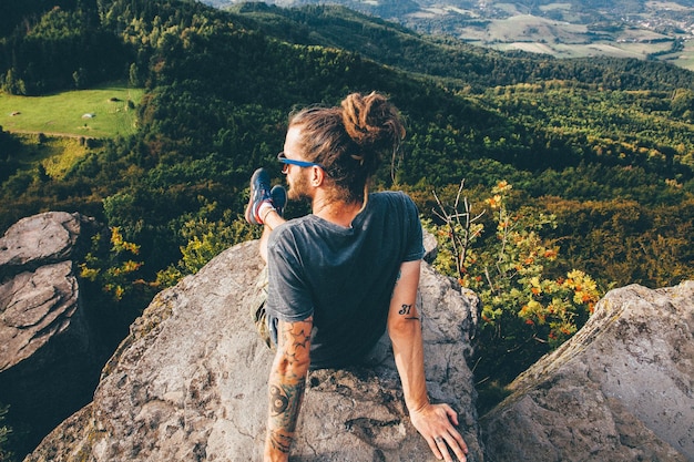 Hintergrundansicht eines Mannes, der auf einem Felsen sitzt