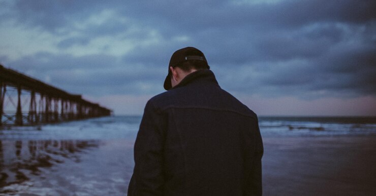 Foto hintergrundansicht eines mannes, der bei sonnenuntergang am strand steht