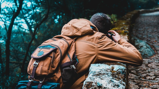 Foto hintergrundansicht eines mannes, der einen rucksack im wald trägt