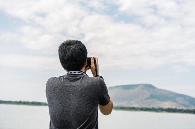 Hintergrundansicht eines Mannes, der gegen den Himmel fotografiert