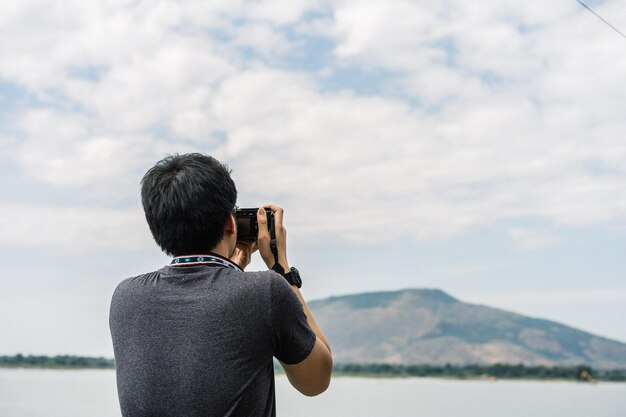 Hintergrundansicht eines Mannes, der gegen den Himmel fotografiert