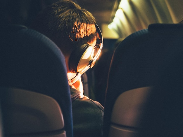 Hintergrundansicht eines Mannes, der im Flugzeug sitzt und Musik hört
