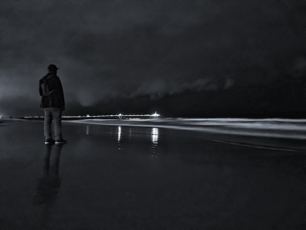 Foto hintergrundansicht eines mannes, der nachts am strand gegen den himmel steht