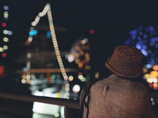 Foto hintergrundansicht eines mannes, der nachts in einer beleuchteten stadt steht