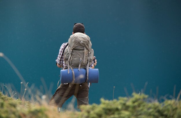 Foto hintergrundansicht eines mannes mit rucksack, der auf dem feld steht