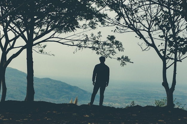 Hintergrundansicht eines Silhouettenmannes, der auf einem Berg steht