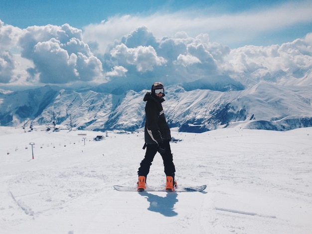 Hintergrundansicht eines Snowboarder gegen schneebedeckte Berge an einem sonnigen Tag
