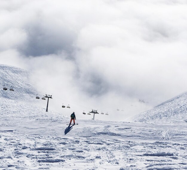 Foto hintergrundansicht eines snowboarders auf einem schneebedeckten berg vor einem bewölkten himmel