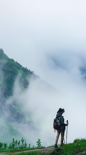 Hintergrundansicht eines Touristen mit Rucksack, der am Rande einer Klippe steht und eine fantastische Aussicht bewundert