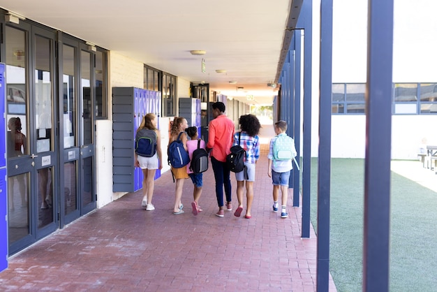 Foto hintergrundansicht verschiedener lehrerinnen und schüler, die zusammen im schulkorridor laufen