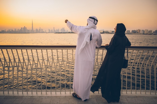 Hintergrundansicht von Frauen, die bei Sonnenuntergang am Meer gegen den Himmel stehen